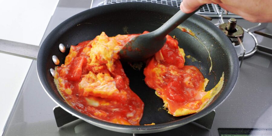 Mixing stir-fried tomatoes with eggs.