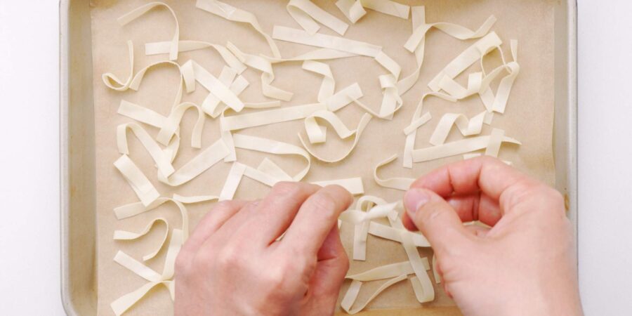 Twisting wonton strips and placing them on a baking sheet.