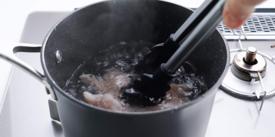 Poaching chicken in a pot of water.