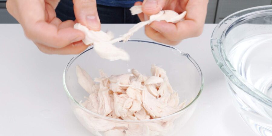 Shredding poached chicken tenders for salad.