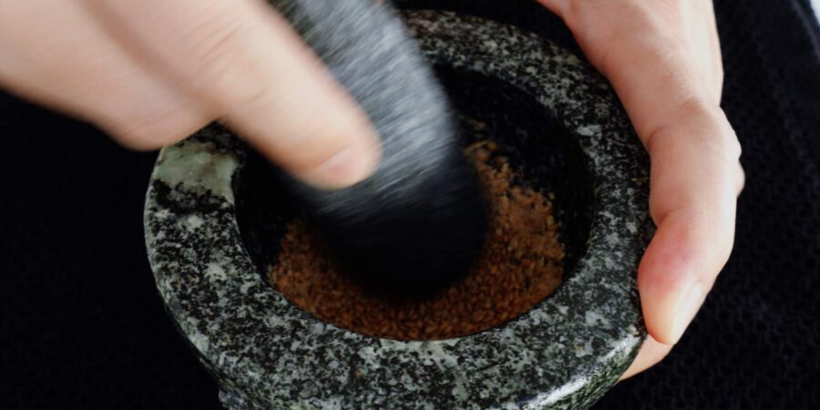 Grinding toasted sesame seeds with a mortar and pestle.