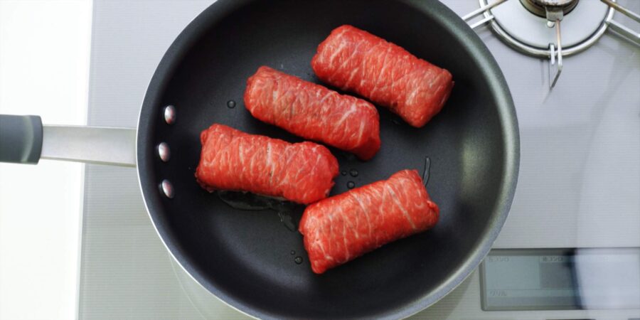 Pan-frying meat wrapped onigiri.