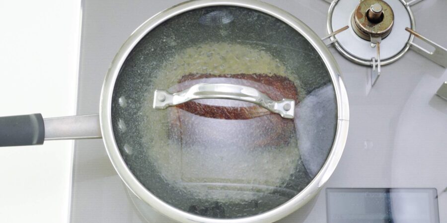 Beef steaming in a pan with a lid.