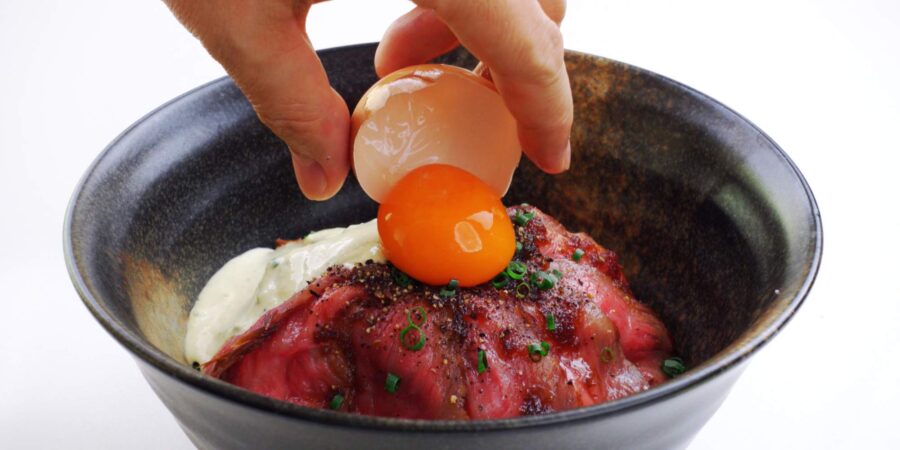 Topping roast beef bowl with an egg yolk.