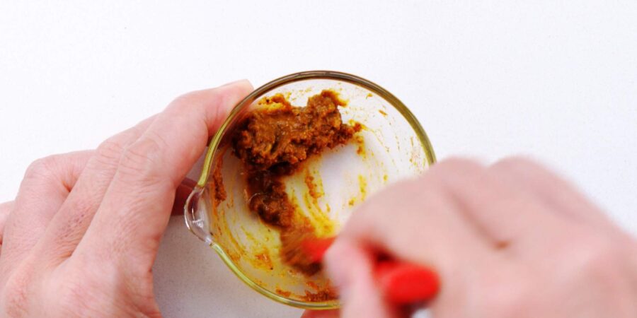 Mixing curry and garlic to make a paste.