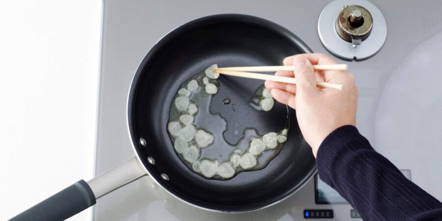 Frying sliced garlic in oil to make garlic chips.