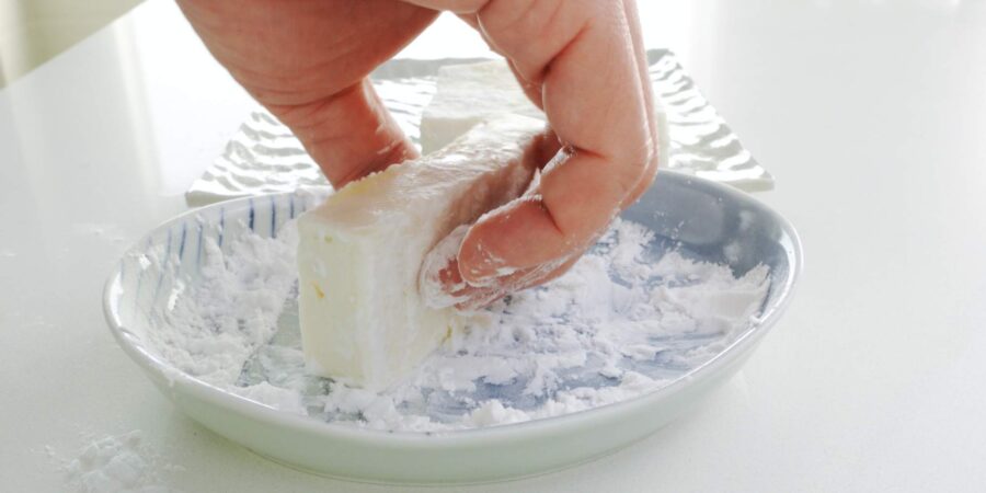 Dusting tofu with potato starch.