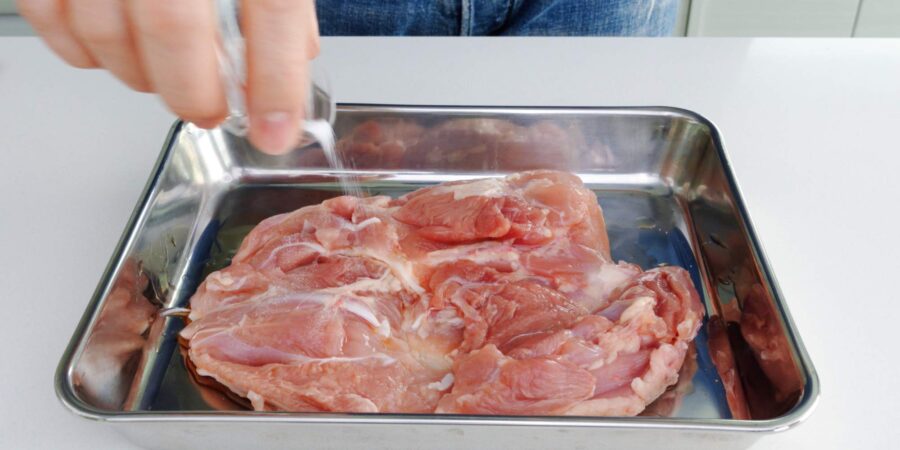 Seasoning chicken leg with salt.