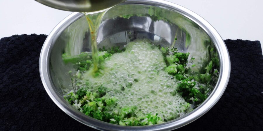 Pouring hot oil over ginger and scallions.