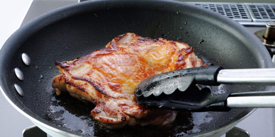 Browning meat-side of chicken in a frying pan.