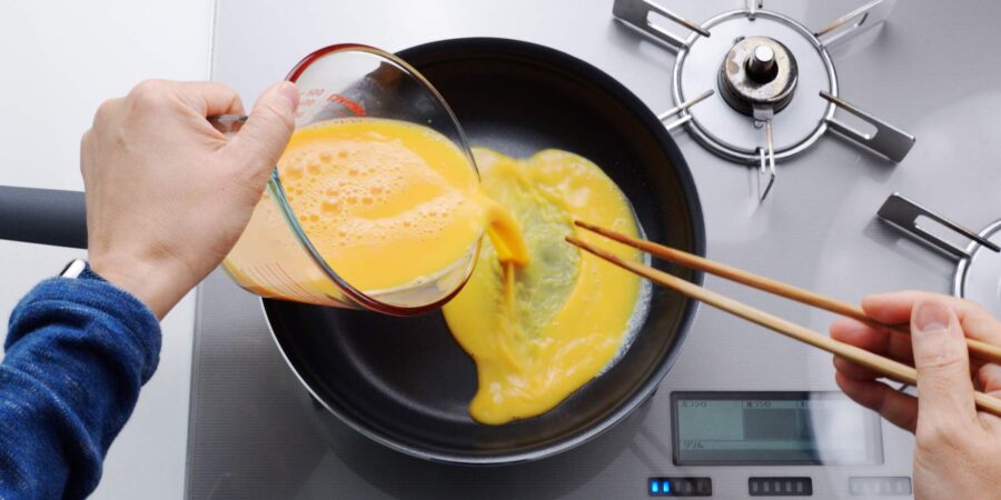 Pouring dashimaki tamago mixture into a hot frying pan.