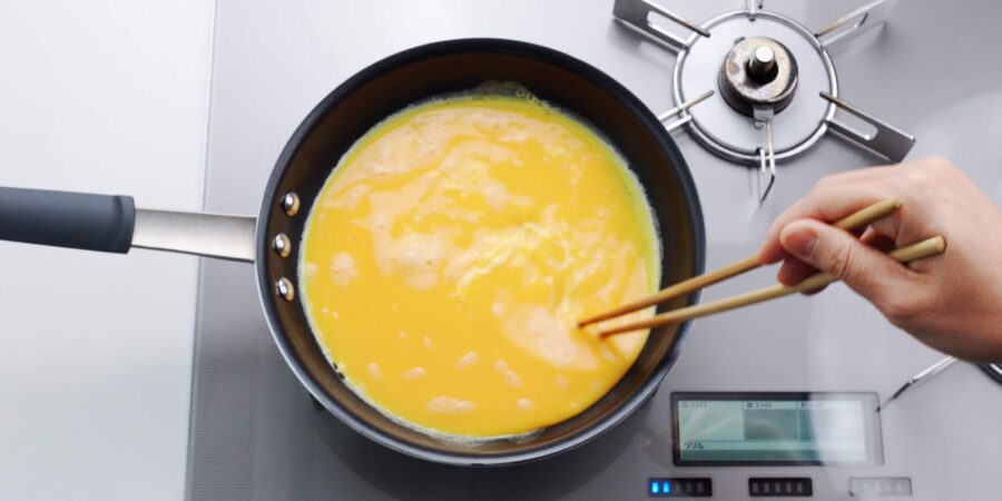 Mixing Japanese omelette egg mixture in a frying pan.