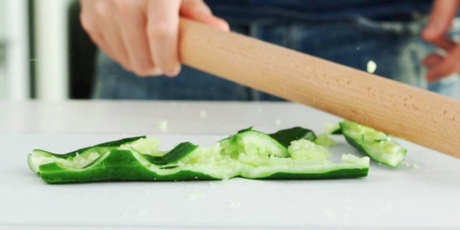 Smashing a cucumber with a rolling pin.