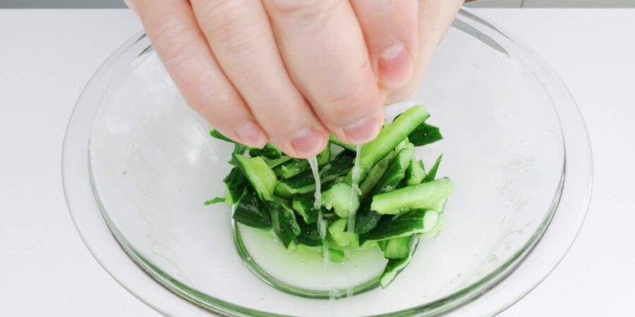 Squeezing excess water out of smashed cucumbers.