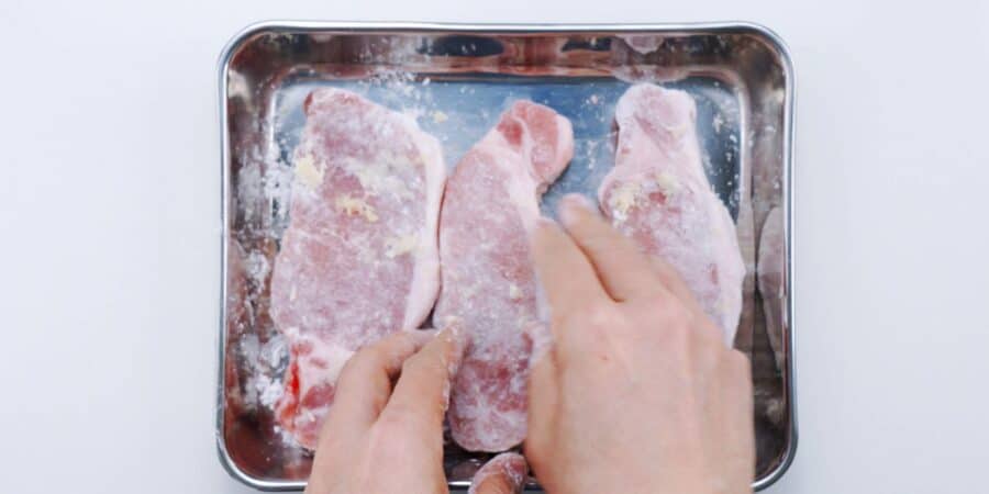 Dusting Japanese pork chops with potato starch.