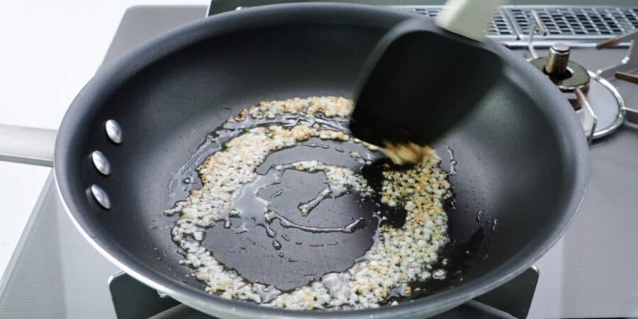 Browning minced garlic in a frying pan with oil.