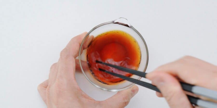 Mixing Traditional Gyoza Sauce in a glass bowl with chopsticks.