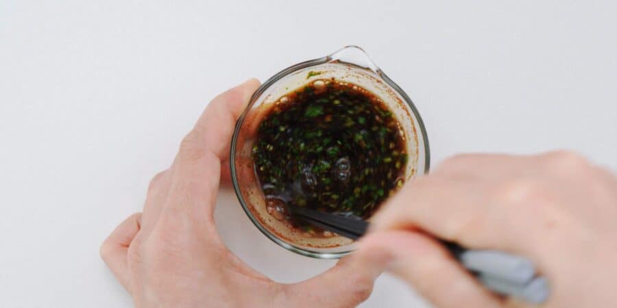 Mixing black vinegar, soy sauce, Chinese five spice, and cilantro together.