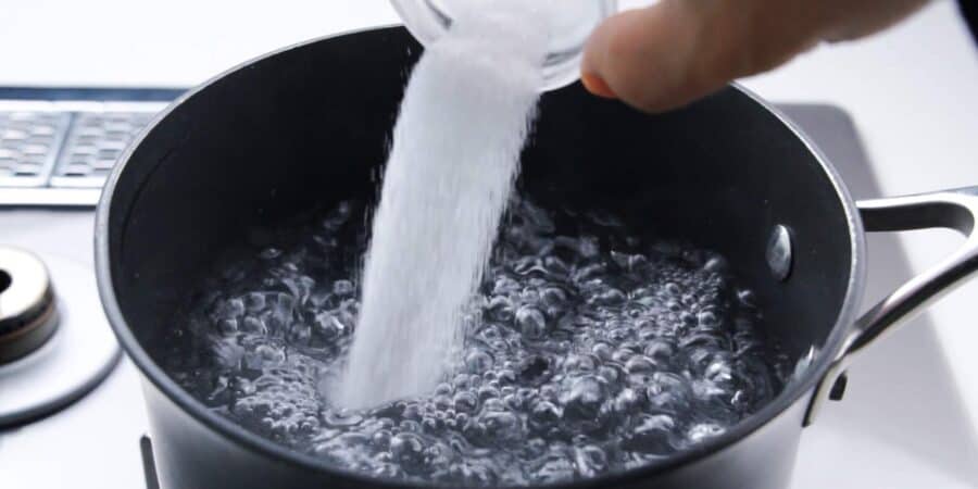 Salting boiling water for pasta.