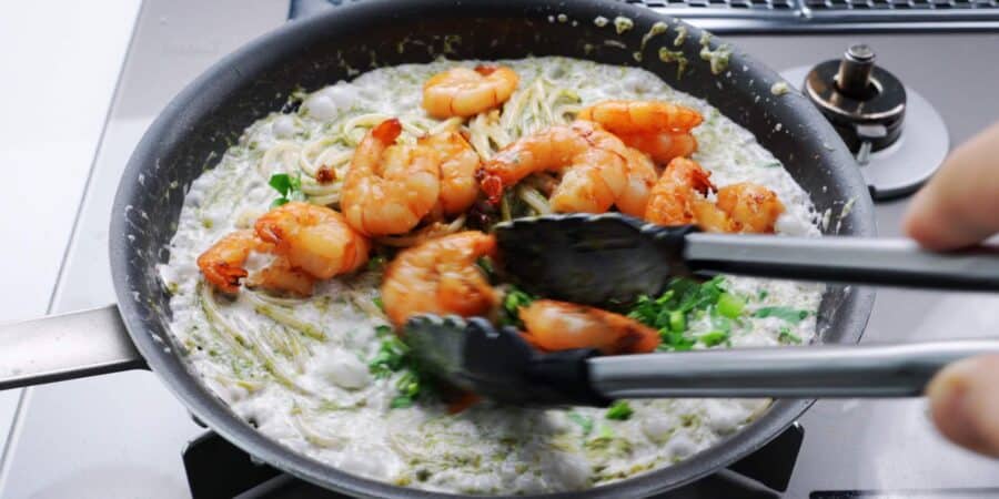 Adding shrimp and watercress to nori cream pasta.