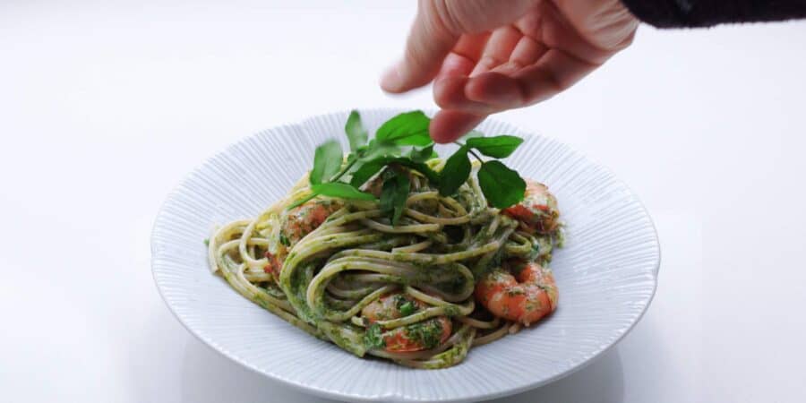 Garnishing a plate of Japanese shrimp pasta with watercress.