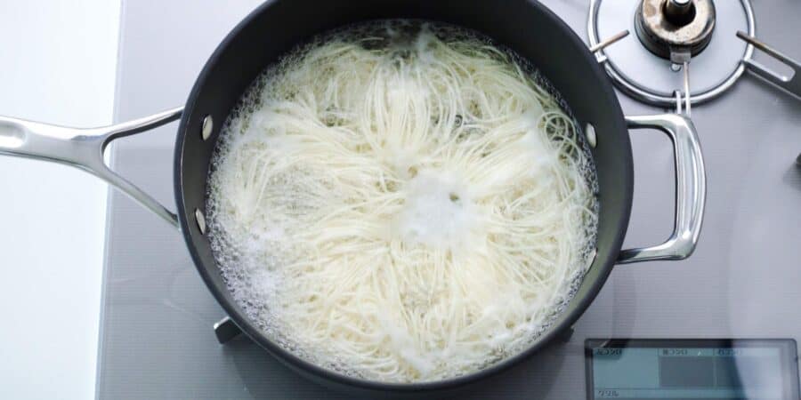 Somen noodles boiling in a large pot.