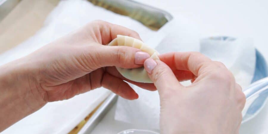 Adding pleats to gyoza as it's being wrapped.