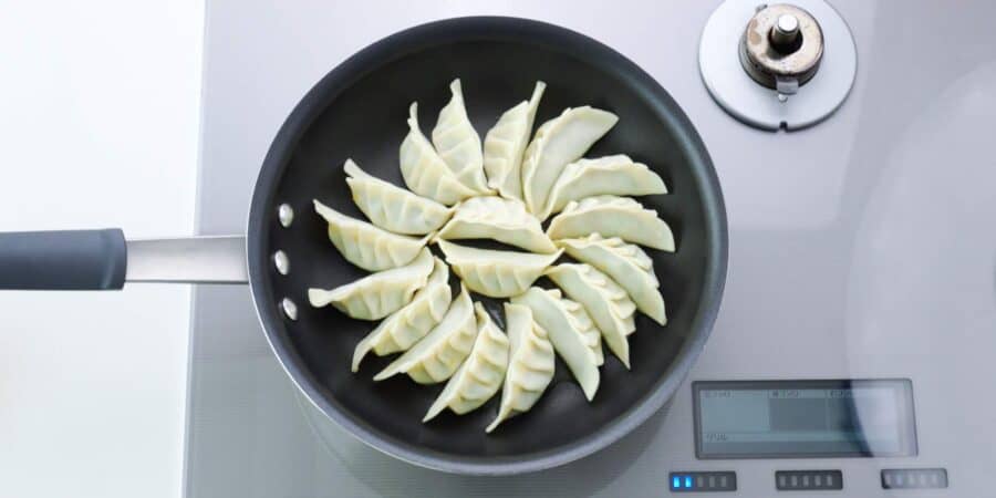 Pan-frying gyoza or Japanese potstickers.