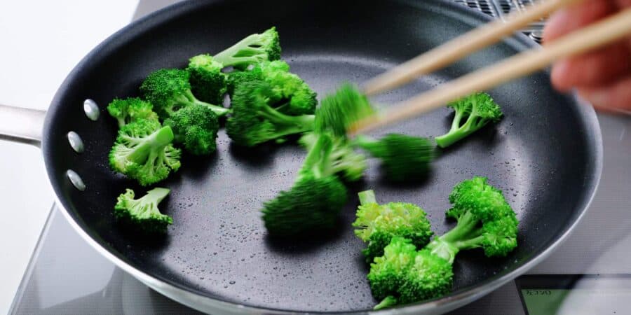 Stir-frying broccoli in frying pan.