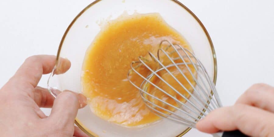 Whisking miso dressing together in a bowl.