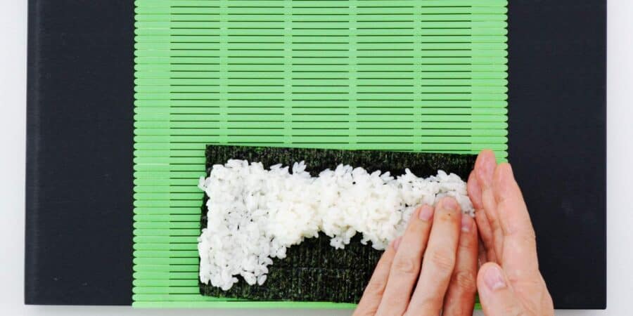 Spreading sushi rice on a nori sheet.