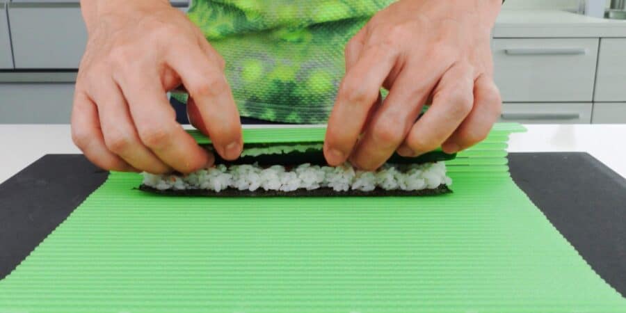 Rolling Kappa Maki sushi rolls with a sushi mat.