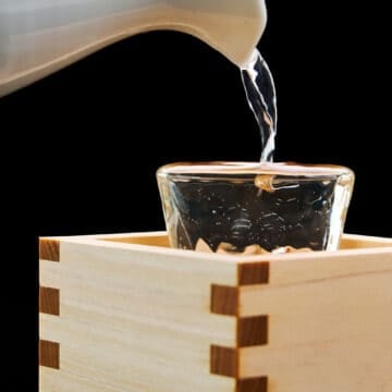 Masuzake overflowing from a glass. This traditional beverage is also an important ingredient in Japanese cooking.