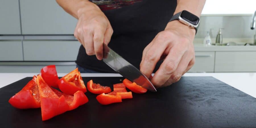 Cutting red peppers on a black cutting board.