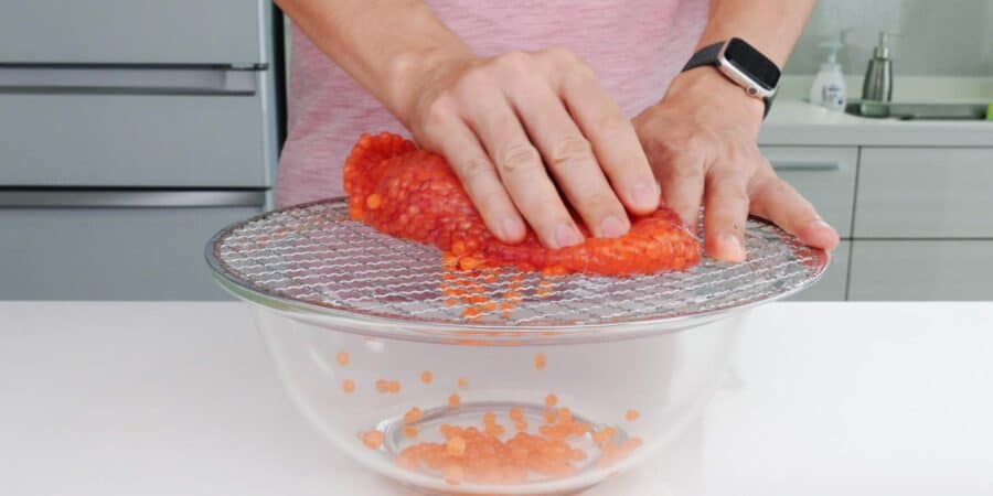 Separating salmon eggs from from roe sack using a mesh grill.