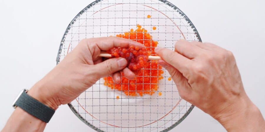 Separating salmon roe from skein using chopsticks.
