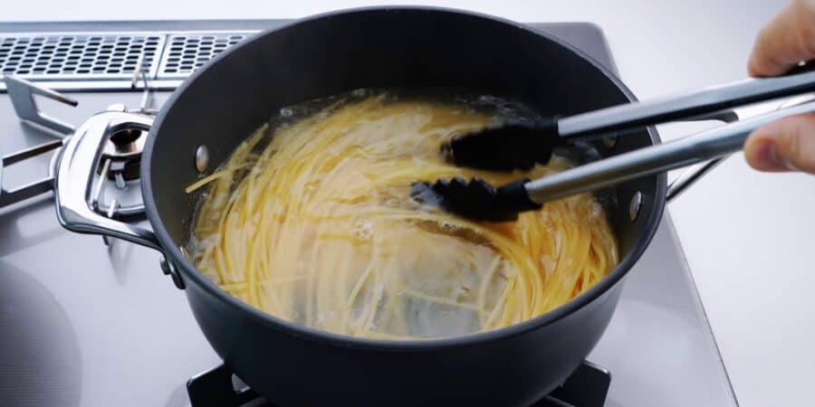 Boiling spaghetti in a wide pot.