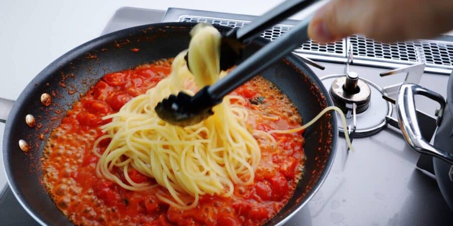 Adding spaghetti to pomodoro sauce.