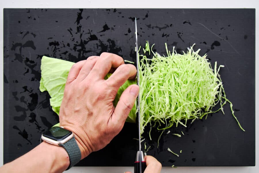 Shredding cabbage into thin ribbons for a Japanese cabbage salad.