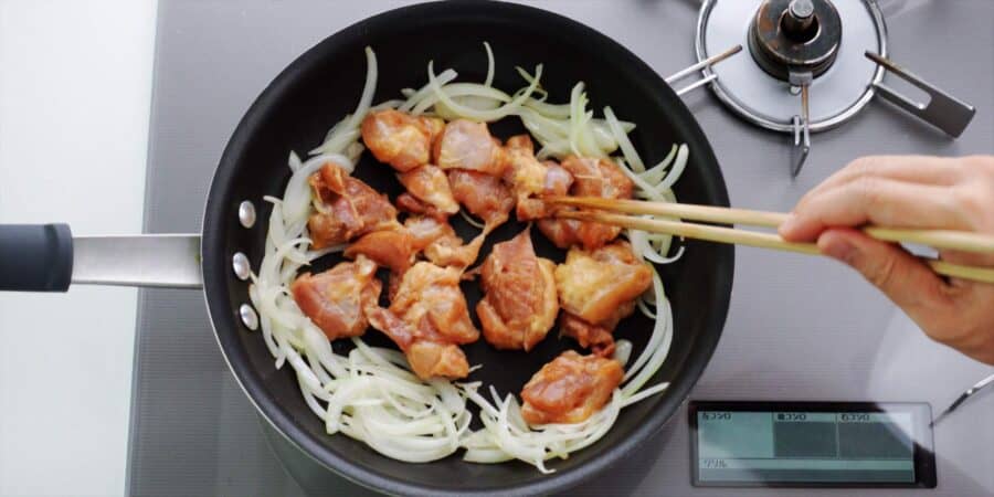 Browning chicken in a frying pan with onions.