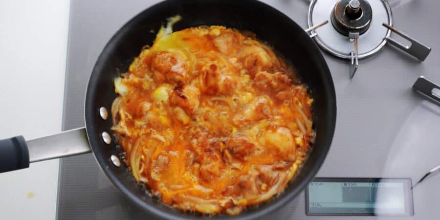 Redistributing egg in a pan of oyakodon by shaking it.