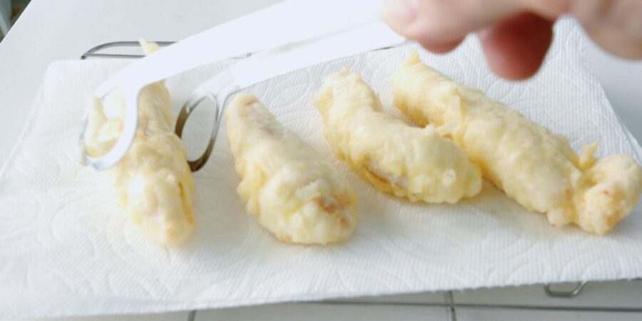 Fried chicken tempura strips draining on paper towels.