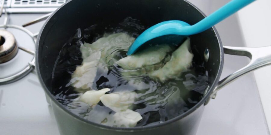 Boiling gyoza in a pot of water.