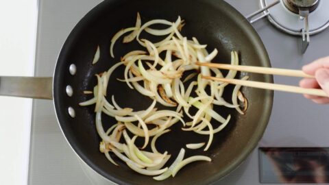 Stir-frying sliced onions for gyudon.
