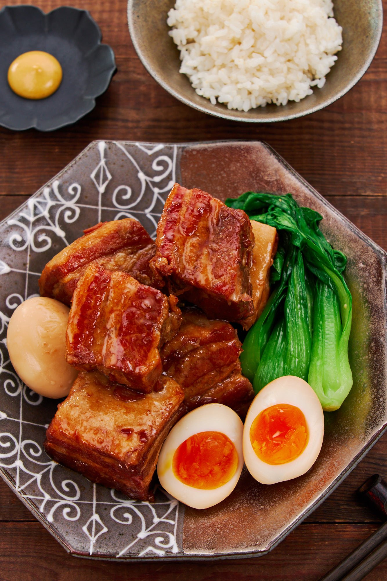 Melt-in-your-mouth tender, pork belly kakuni cubes bathe in a rich, umami-laden sauce, paired with vibrant bok choy, golden soft-boiled eggs, and a steaming bowl of rice for the ultimate comfort meal.