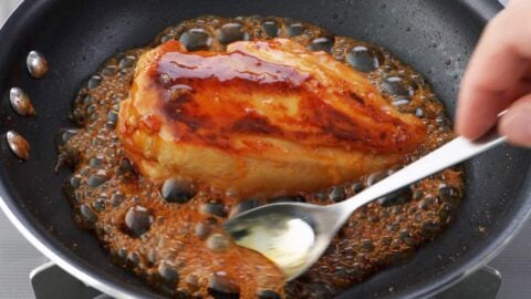Glazing chicken with honey teriyaki sauce.