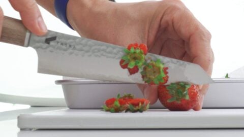 Slicing tops off of strawberries.
